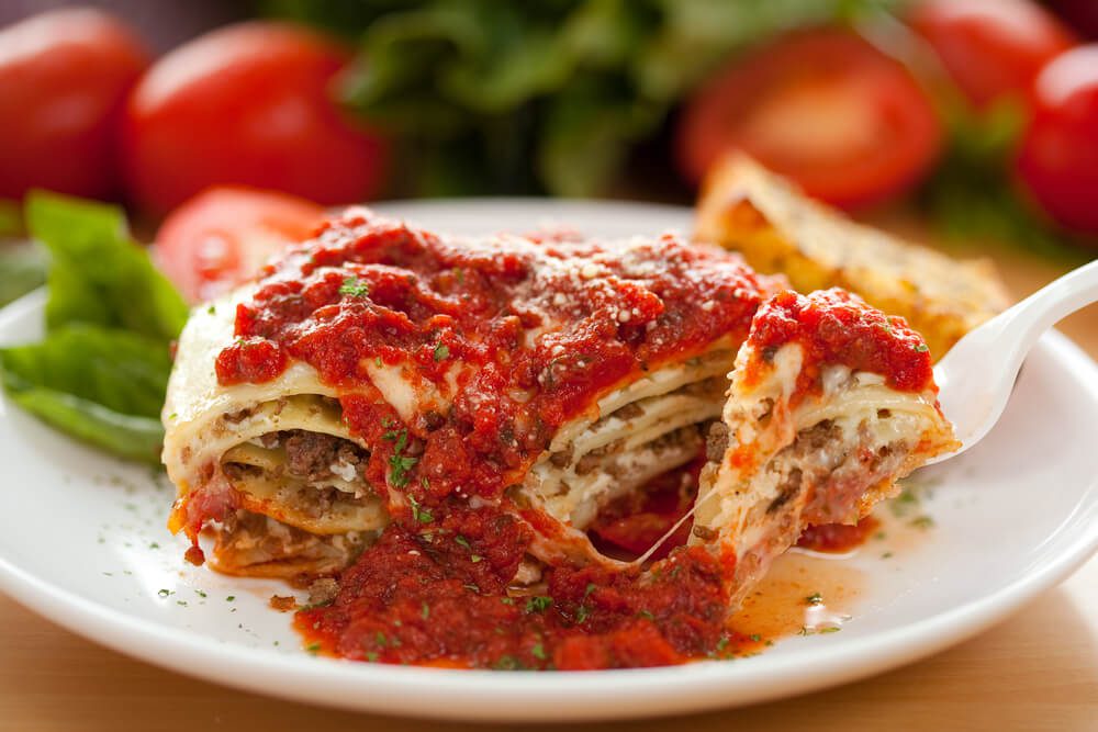 Slice of lasagna with tomato sauce.