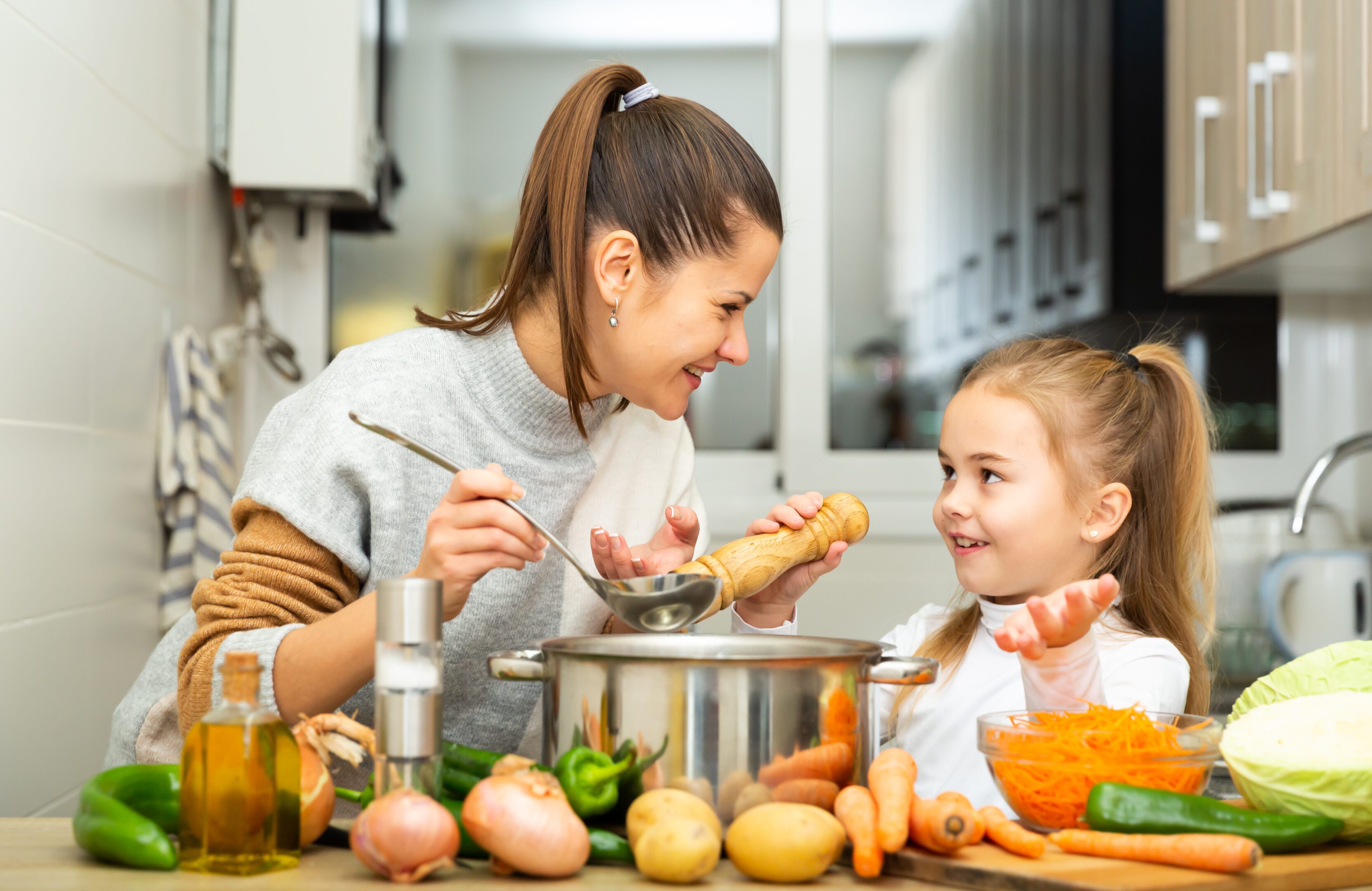 Mother and daughter cooking in kitchen together.