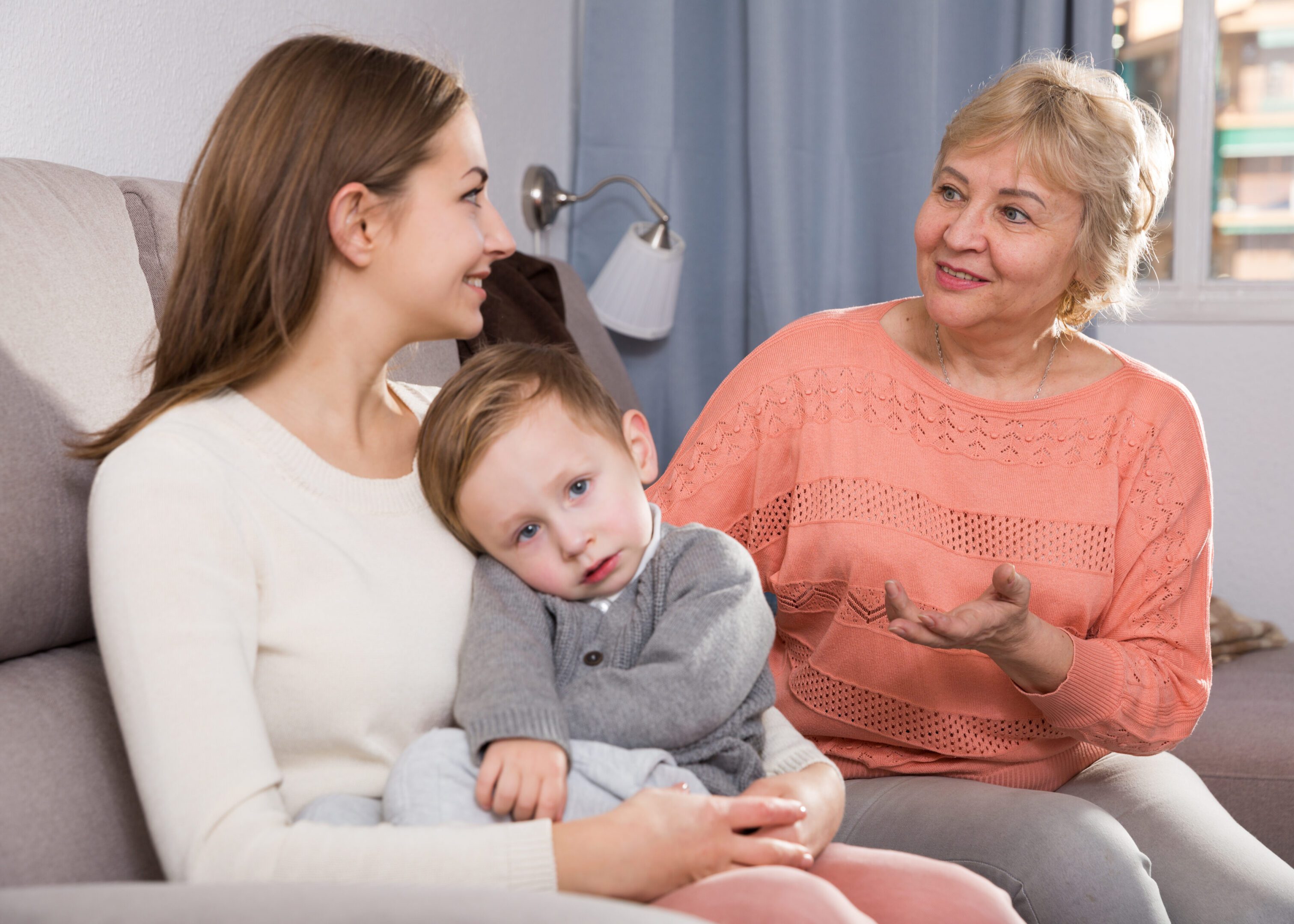 Grandmother, mother, and child sitting together talking.