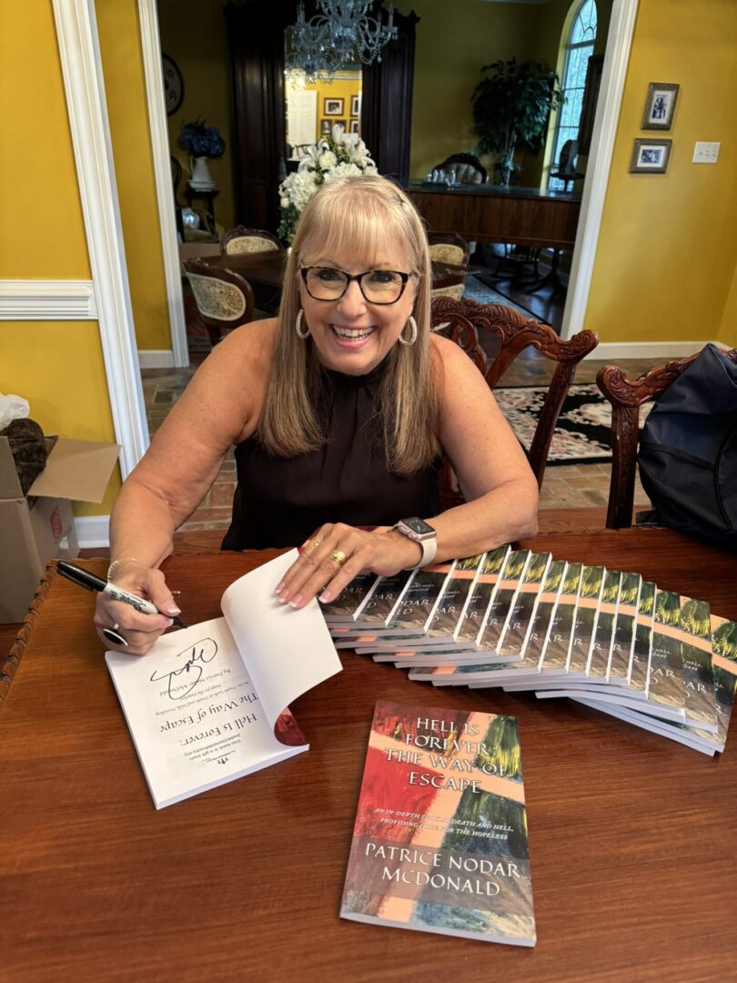 Woman signing books at a table.