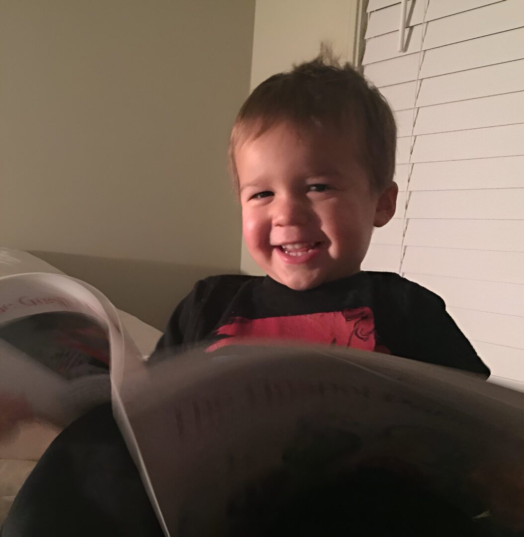 Smiling toddler holding an open book.
