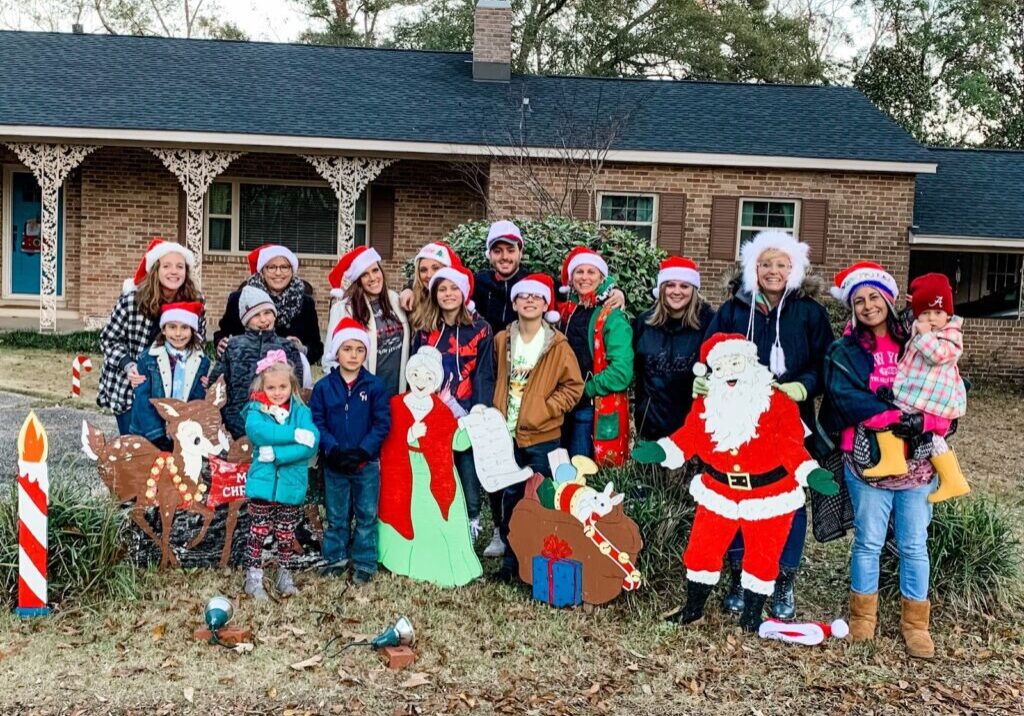 Group of children and adults in Christmas attire posing outdoors.