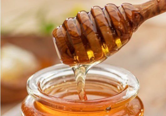 Natural organic honey in glass jar, honey dipper and honeycombs are near. Natural food background.